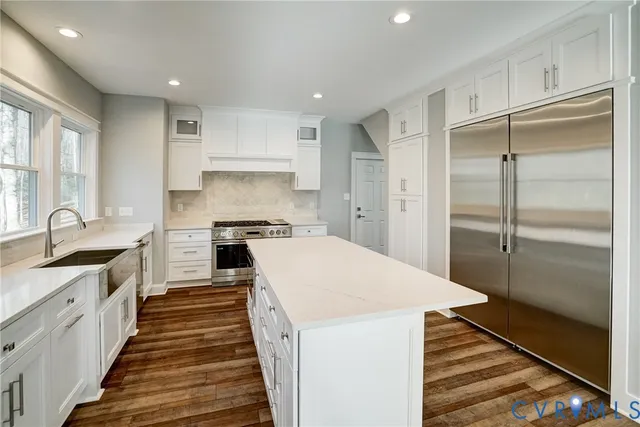 a large kitchen with a refrigerator a sink and white cabinets