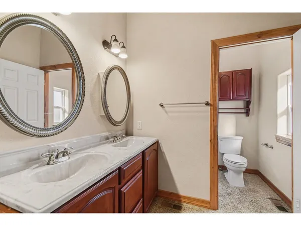 a bathroom with a granite countertop toilet a sink and a mirror