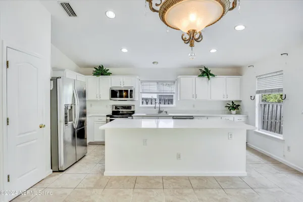 a view of kitchen with stainless steel appliances granite countertop a refrigerator oven a sink dishwasher and white cabinets with wooden floor