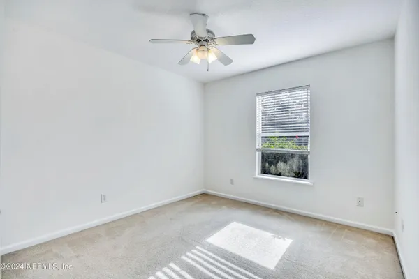 an empty room with a window and a ceiling fan