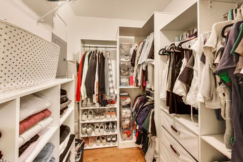 a view of walk in closet with clothes and shoes