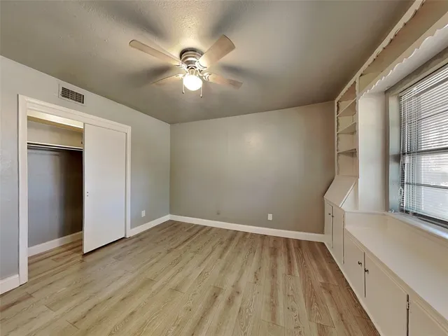 a view of empty room with wooden floor and fan