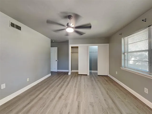 a view of an empty room with a window and wooden floor