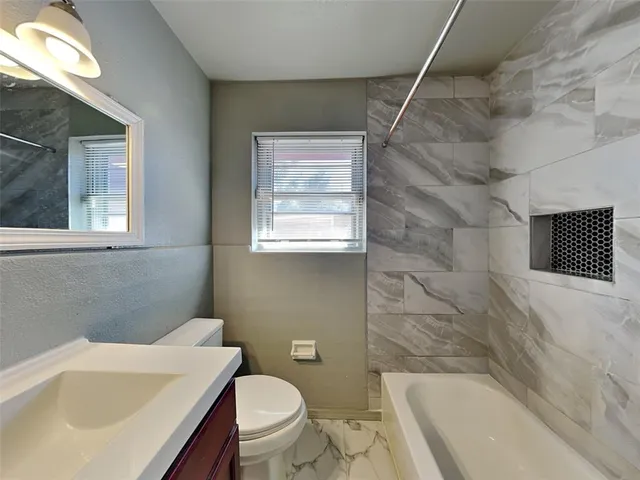 a bathroom with a sink a toilet a mirror and bathtub
