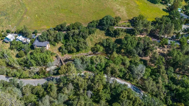 an aerial view of residential house with outdoor space and trees all around