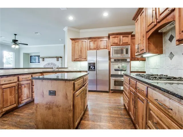 a kitchen with kitchen island granite countertop a sink cabinets and wooden floor