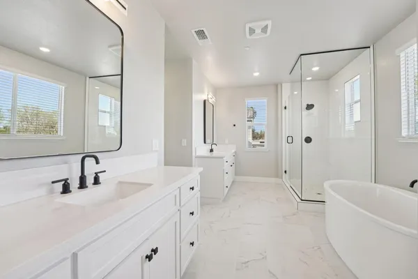 a bathroom with a double vanity sink toilet mirror and bathtub