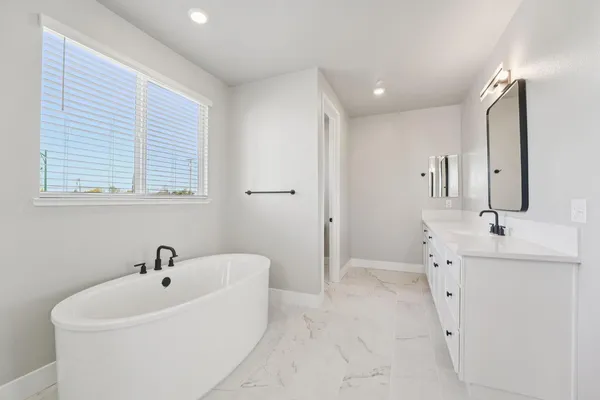 a spacious bathroom with a bathtub sink and mirror