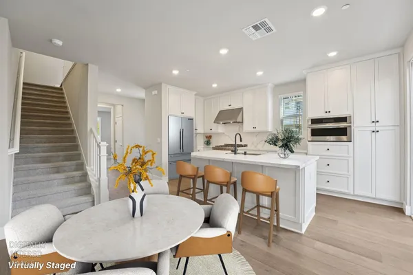 a kitchen with stainless steel appliances kitchen island granite countertop a table chairs and a refrigerator