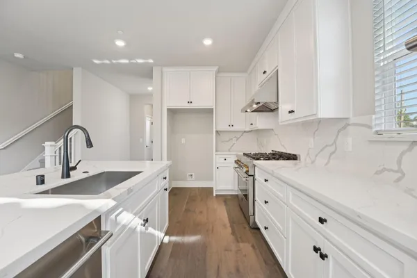 a kitchen with stainless steel appliances granite countertop a sink stove and white cabinets