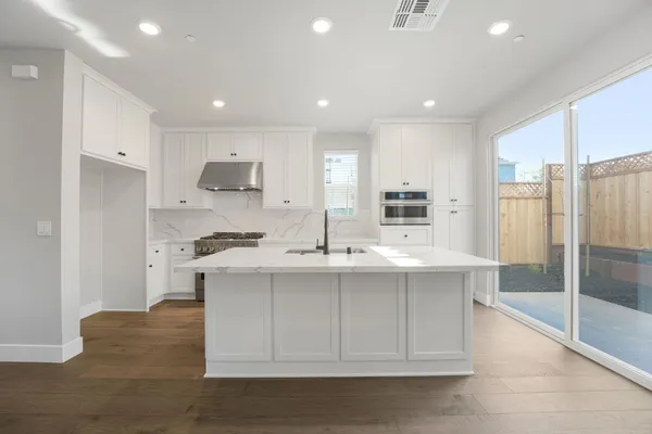 a kitchen with kitchen island sink stove and refrigerator