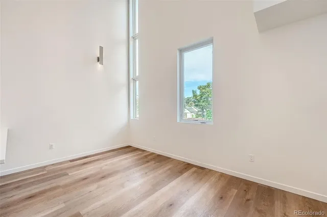 a view of hallway with window and wooden floor