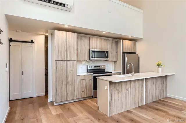 a kitchen with stainless steel appliances granite countertop a stove top oven a sink dishwasher and a refrigerator with wooden floor