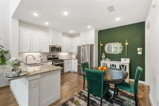 a kitchen with stainless steel appliances granite countertop sink stove refrigerator dining table and chairs