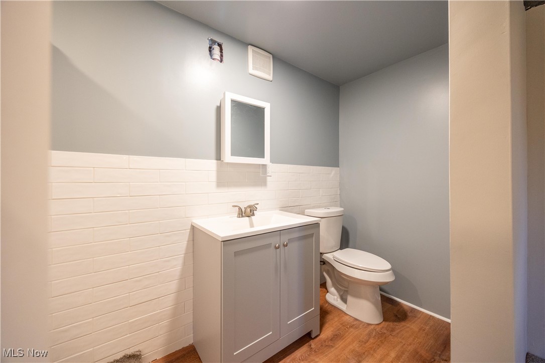 3797 Northwood Road Cleveland, OH 44118 - Photo 38 of 49 Half bath featuring light wood-style floors, vanity, tile walls, and wainscoting