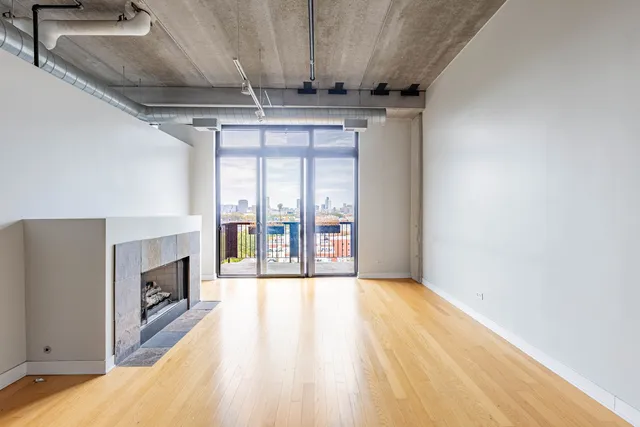 a view of an empty room with wooden floor and a fireplace