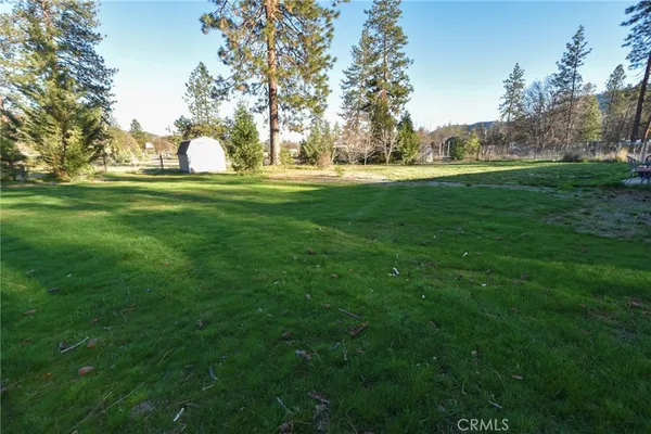 a view of grassy field with benches and trees all around