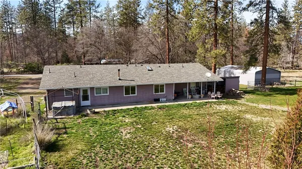 a aerial view of a house next to a yard with plants and large trees