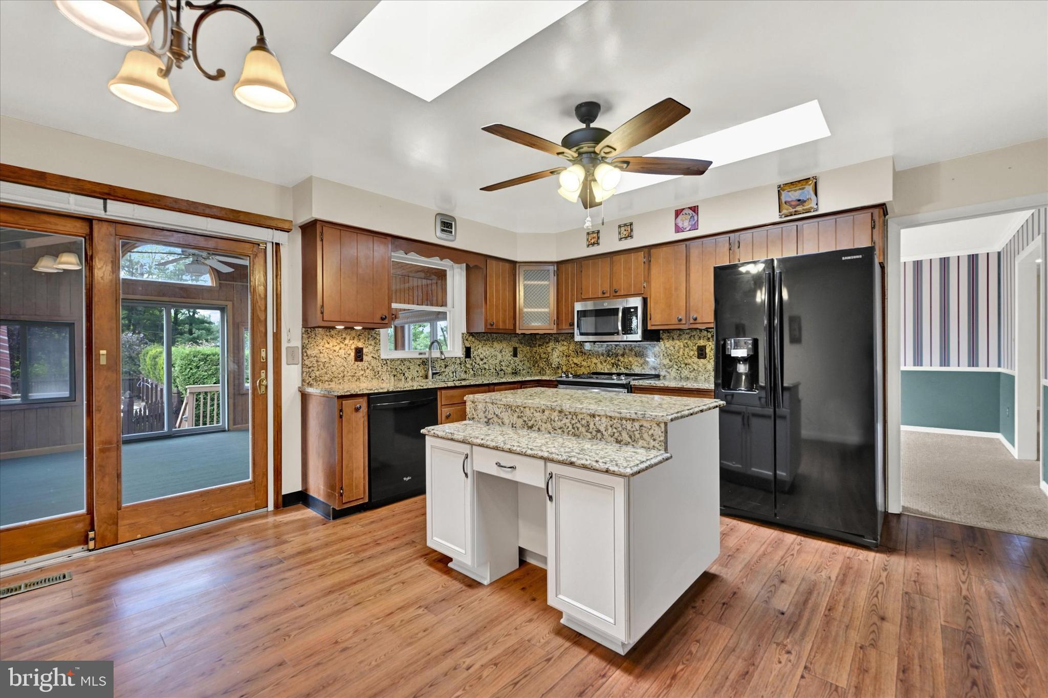 4009 Eland Road Phoenix, MD 21131 - Photo 10 of 38 a kitchen with stainless steel appliances granite countertop a refrigerator a sink dishwasher a stove and a dining table with wooden floor