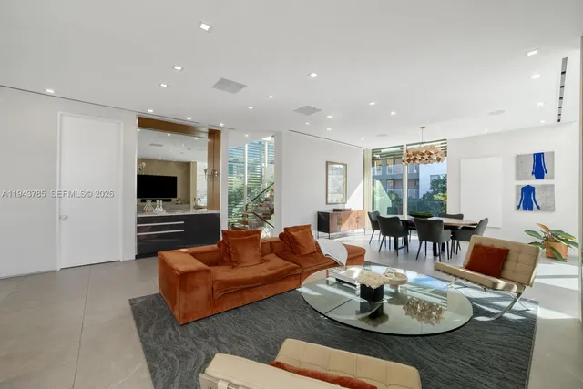 a living room with furniture kitchen view and a large window