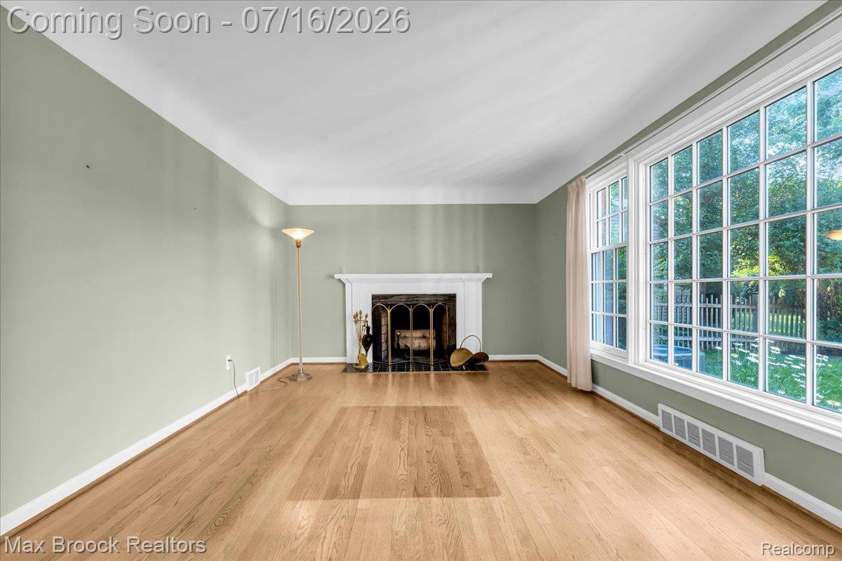 1292 Yorkshire Road Birmingham, MI 48009 - Photo 5 of 47 Expansive room featuring wood-finish flooring, a white mantel fireplace with a black surround, and large multi-pane windows overlooking a manicured lawn