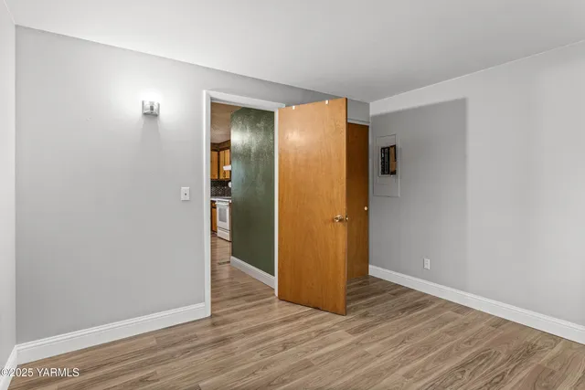 a view of an empty room with wooden floor and closet