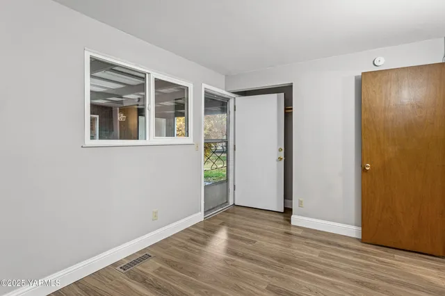 a view of an empty room with wooden floor and a window