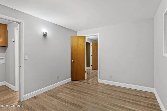 a view of an empty room with wooden floor and closet