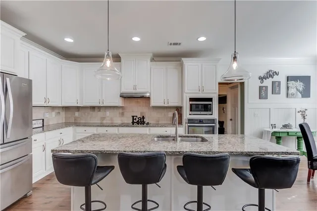 a kitchen with granite countertop a table chairs stove and white cabinets
