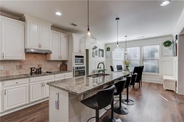 a large kitchen with granite countertop a stove a sink a dining table and chairs