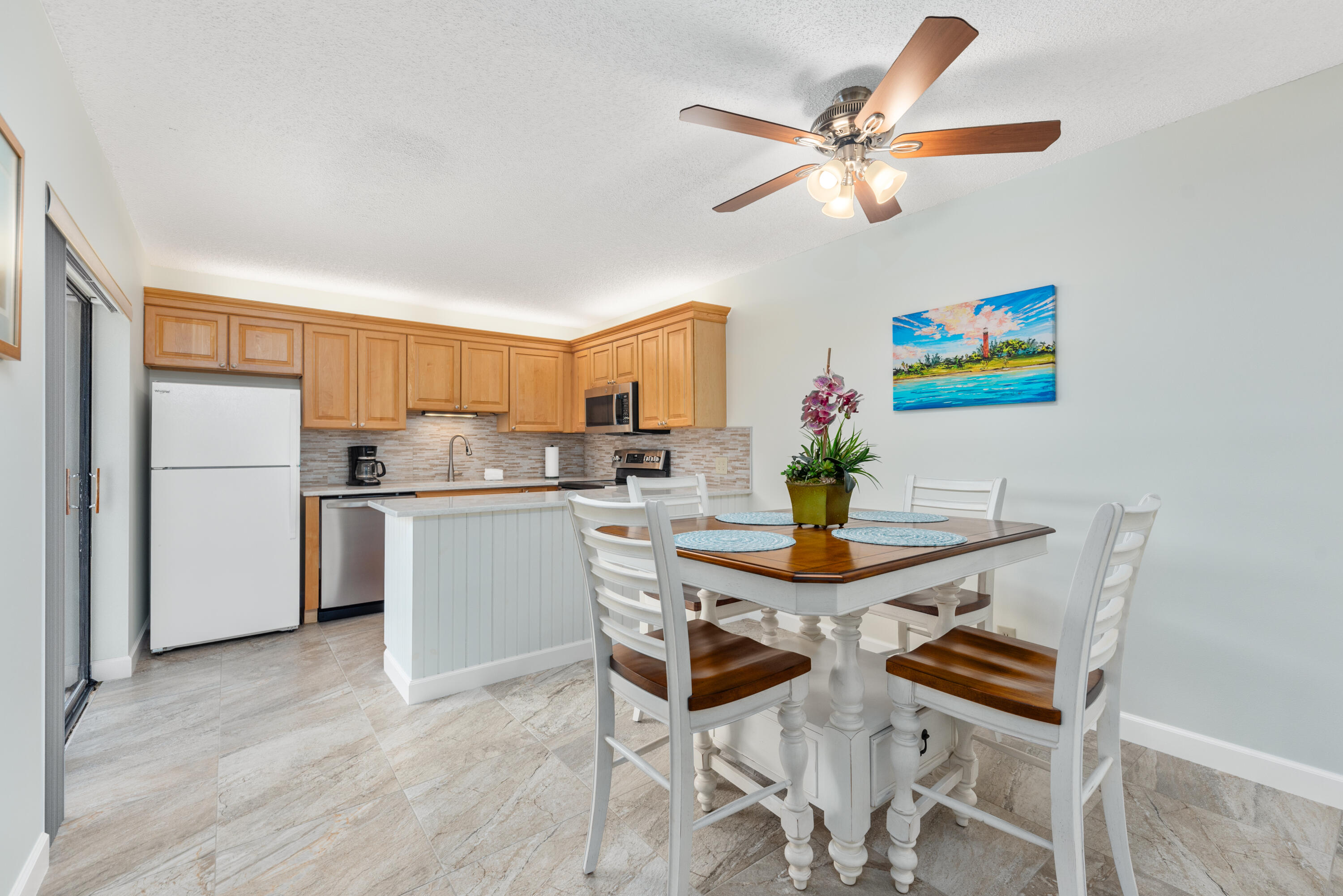 5874 Southeast Riverboat Drive, Unit 330 Stuart, FL 34997 - Photo 10 of 40 a dining room with kitchen island stainless steel appliances a stove a table and chairs