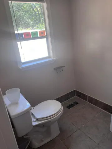 a white toilet sitting in a bathroom next to a window