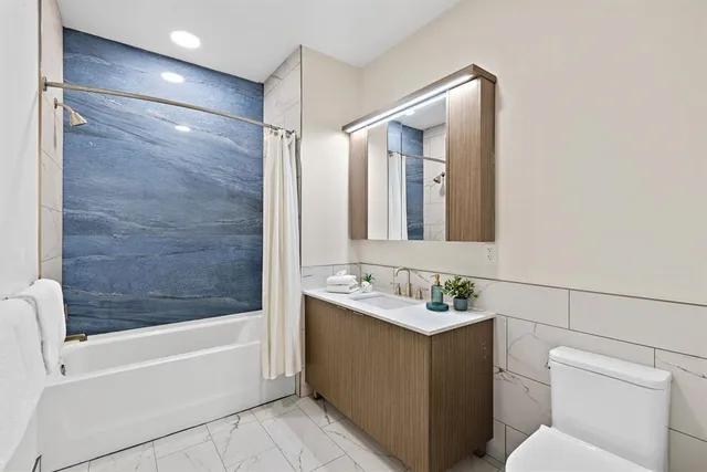 a bathroom with a bathtub shower sink vanity and toilet