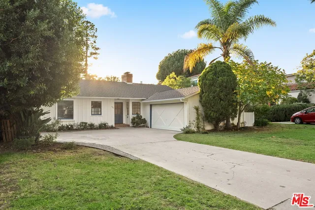 a front view of a house with a garden and trees