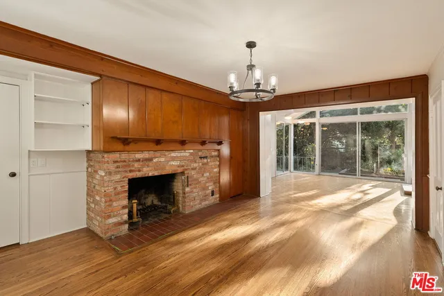 a view of an empty room with wooden floor fireplace and a window