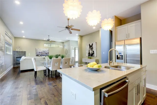 a kitchen with a sink dishwasher a dining table and chairs with wooden floor