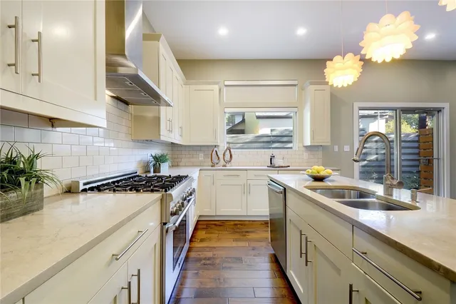 a kitchen with stainless steel appliances granite countertop a sink a stove and a wooden floors