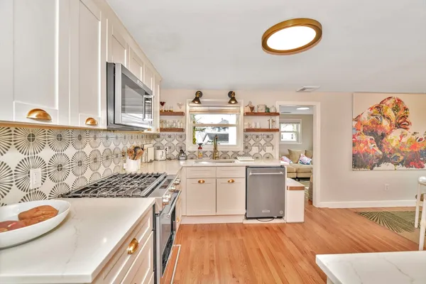 a kitchen with stainless steel appliances granite countertop a stove a sink and a microwave