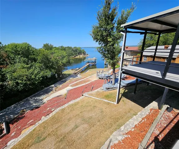 a backyard of a house with table and chairs under an umbrella