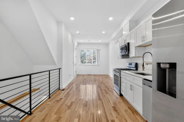 a kitchen with granite countertop a stove top oven a sink dishwasher and white cabinets with wooden floor