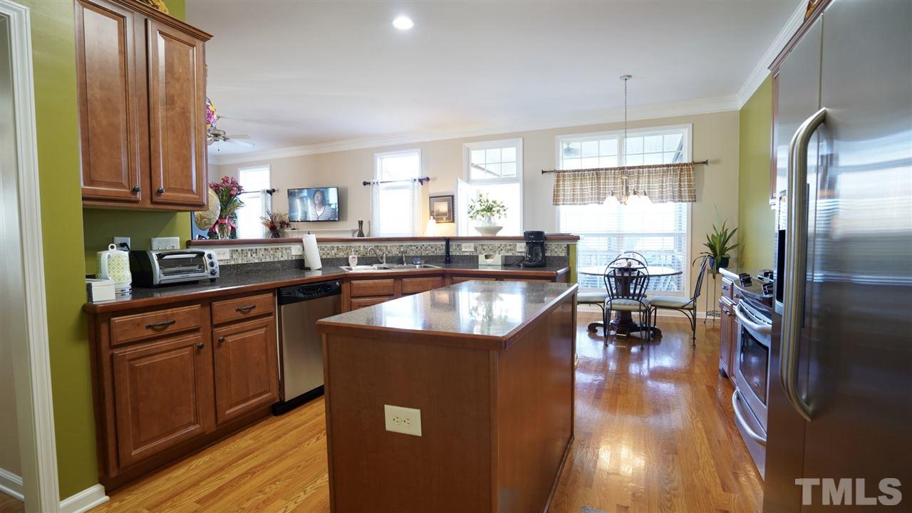 116 Okamato Street Raleigh, NC 27603 - Photo 7 of 19 a kitchen with stainless steel appliances granite countertop a refrigerator a sink dishwasher a stove and a dining table with wooden floor