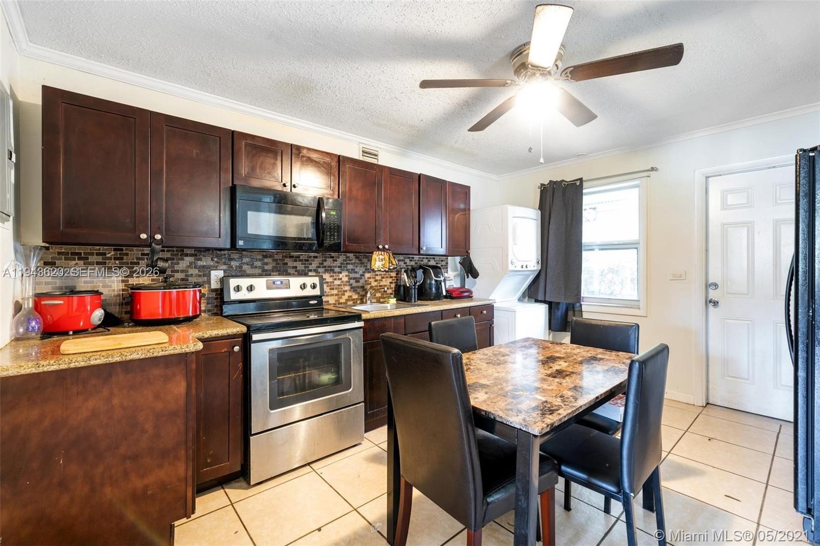 438 Northwest 93rd Street, Unit 440 Miami, FL 33150 - Photo 8 of 13 a kitchen with granite countertop wooden cabinets a stove a sink and a refrigerator