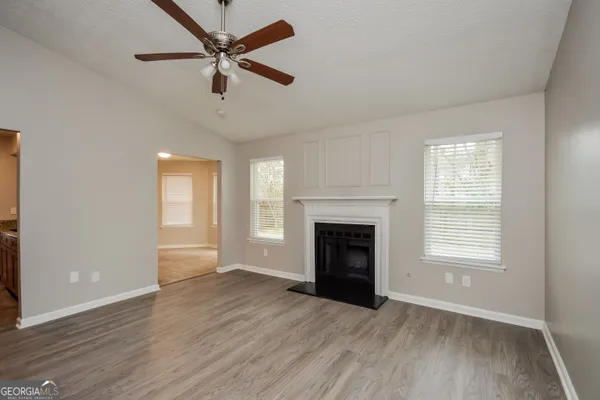 an empty room with windows a fireplace and a wooden floor