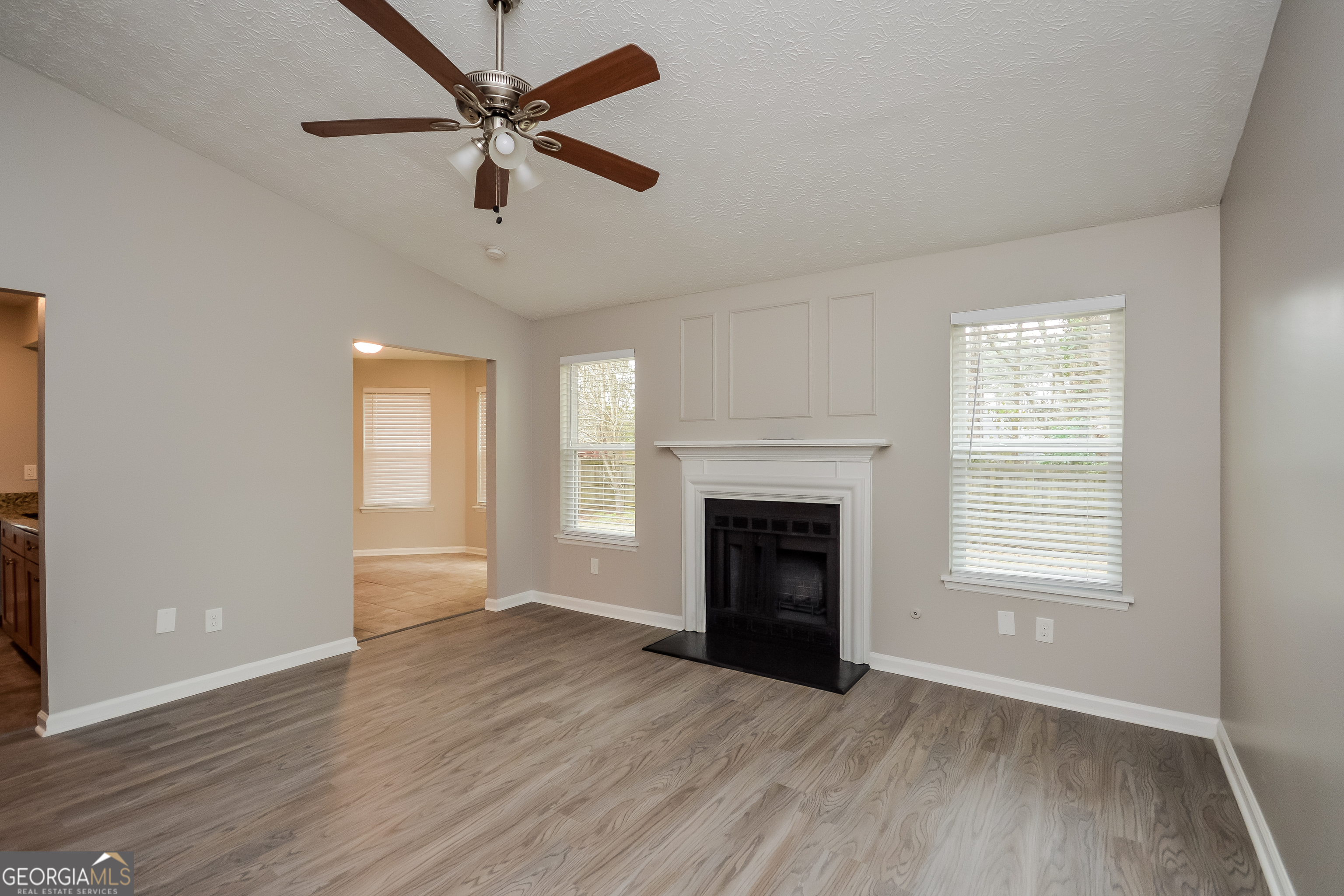 5456 Panola Downs Road Lithonia, GA 30058 - Photo 3 of 16 an empty room with windows a fireplace and a wooden floor