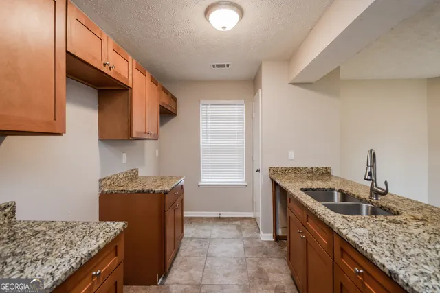 a kitchen with granite countertop a sink a stove and a wooden cabinets