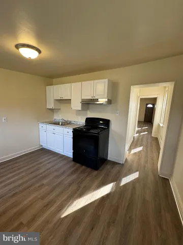 a kitchen with granite countertop a sink cabinets and wooden floor