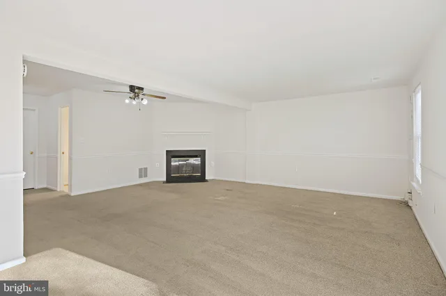 a view of an empty room with a chandelier fan