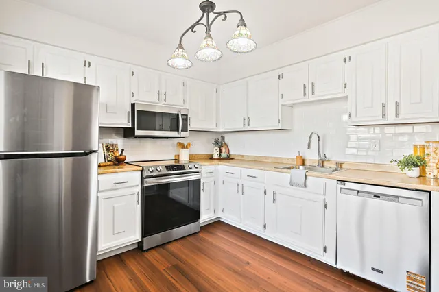 a kitchen with cabinets stainless steel appliances and wooden floors