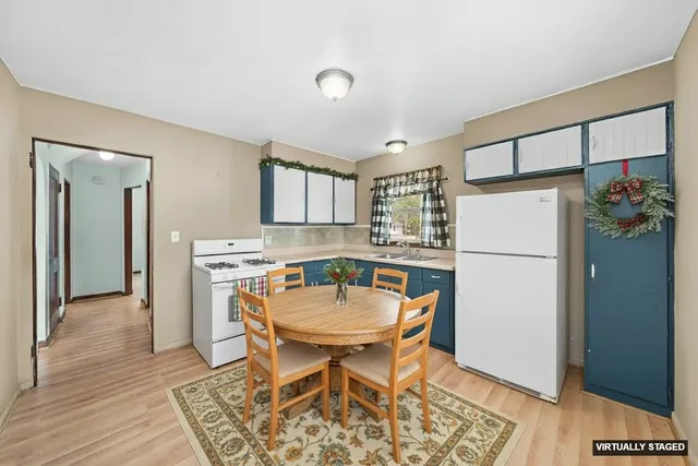 a kitchen with a refrigerator a table and chairs in it