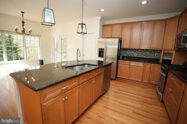 a kitchen with stainless steel appliances granite countertop a sink a stove and a refrigerator